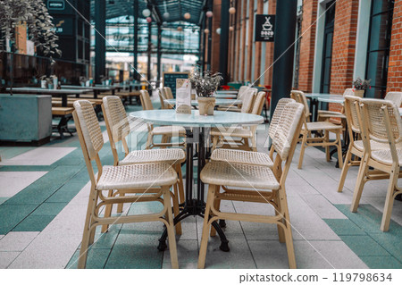 Wooden chairs with a green flowers in the middle of the table of an outdoor restarurant 119798634