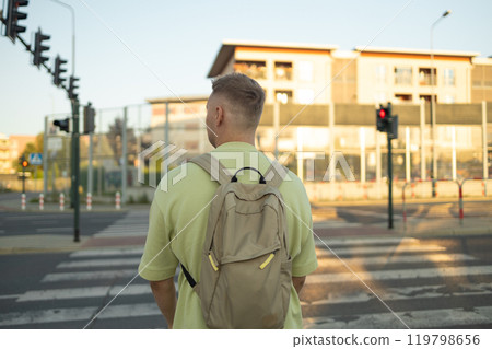 Back view of Caucasian man with blonde hair and backpack walking on street of Krakow city 119798656