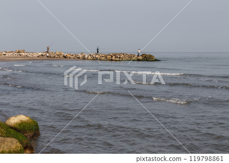 Fishermen stand on the shore and catch fish with a fishing rod. Caspian Sea, Iran 119798861