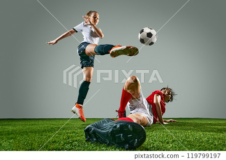 Dynamic image of two young women, soccer players competing on field, showing skills and motivation to win. Woman in white jersey hitting ball in mid-air 119799197
