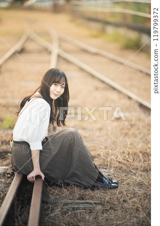 Woman sitting on abandoned railway line 119799372