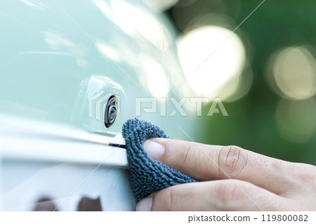 Car owner cleans the front dashcam lens with a cloth, emphasizing the importance of clear footage and safety through maintaining a reliable in-car camera Car owner cleans the front dashcam lens with a cloth, emphasizing the importance of clear footage and safety through maintaining a reliable in-car camera 119800082