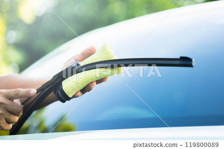 Car owner cleans the windshield wipers with a cloth, highlighting the importance of regular maintenance for optimal performance and clear visibility in all weather conditions Car owner cleans the windshield wipers with a cloth, highlighting the importance of regular maintenance for optimal performance and clear visibility in all weather conditions 119800089