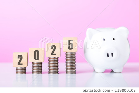 A stack of coins placed on top of a wooden block labeled '2025.' The image symbolizes financial growth and planning for the year ahead, highlighting the importance of saving and investment strategies 119800102