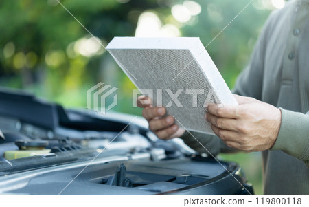 Car owner holds an air filter for examination. Importance of regular inspection, cleaning, and replacement of car air filters, Emphasizes maintenance for better air quality and vehicle efficiency Car owner holds an air filter for examination. Importance of regular inspection, cleaning, and replacement of car air filters, Emphasizes maintenance for better air quality and vehicle efficiency 119800118