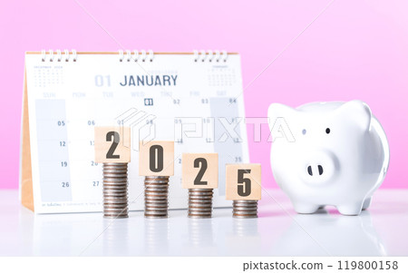 A Stack of coins beside a wooden block labeled '2025' and a calendar. Symbolizes financial planning for the upcoming year, emphasizing budgeting and setting future investment goals 119800158