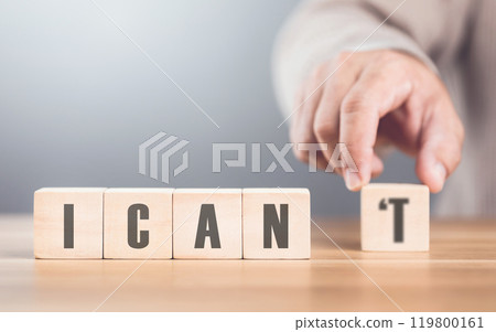 Hand separates the letter "T" from the word "I CAN'T" transforming it into "CAN" The image symbolizes overcoming obstacles, shifting from doubt to empowerment, and embracing a positive mindset 119800161