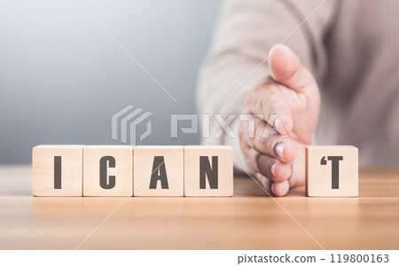 Hand separates the letter "T" from the word "I CAN'T" transforming it into "CAN" The image symbolizes overcoming obstacles, shifting from doubt to empowerment, and embracing a positive mindset Hand separates the letter "T" from the word "I CAN'T" transforming it into "CAN" The image symbolizes overcoming obstacles, shifting from doubt to empowerment, and embracing a positive mindset 119800163