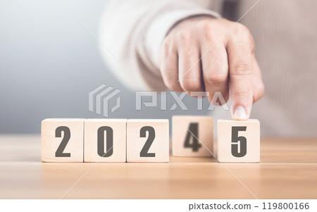 Hand replaces "2024" with "2025" using number blocks, symbolizing the transition into the new year, representing change, progress, and the ongoing passage of time 119800166