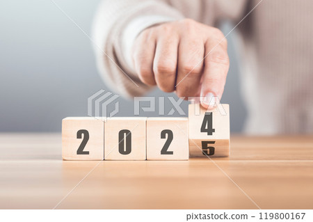 Hand replaces "2024" with "2025" using number blocks, symbolizing the transition into the new year, representing change, progress, and the ongoing passage of time 119800167