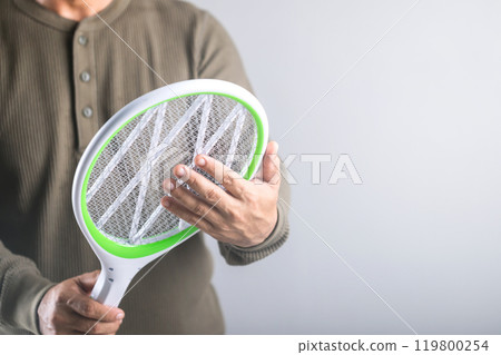 A Man is holding the swatter and touching its circuit, Whether it poses a physical danger to the human body. Concept explores whether a person can touch the circuit of an electric mosquito swatter A Man is holding the swatter and touching its circuit, Whether it poses a physical danger to the human body. Concept explores whether a person can touch the circuit of an electric mosquito swatter 119800254