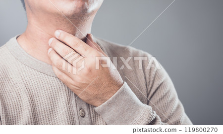 Man experiencing throat pain from overusing his voice, placing his hand on his throat in discomfort. The concept focuses on vocal strain and its impact on health and well-being 119800270