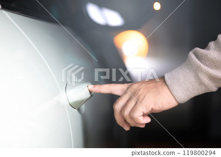A man's hand touching the car door to unlock it without using a remote or key. Represents the concept of modern vehicle technology, highlighting keyless entry systems for convenience and security 119800294