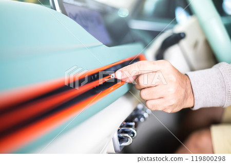Car owner adjusts the direction of the air vent by hand, ensuring optimal airflow in the vehicle. Proper vehicle maintenance and correct air conditioning usage for a comfortable driving experience 119800298