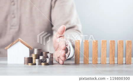 Businessman uses his hand to stop wooden blocks from falling, symbolizing the protection of assets and strategic decision-making in managing resources effectively, domino effect and risk management Businessman uses his hand to stop wooden blocks from falling, symbolizing the protection of assets and strategic decision-making in managing resources effectively, domino effect and risk management 119800300