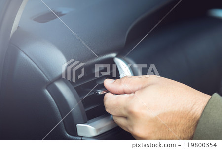 Car owner adjusts the direction of the air vent by hand, ensuring optimal airflow in the vehicle. Proper vehicle maintenance and correct air conditioning usage for a comfortable driving experience Car owner adjusts the direction of the air vent by hand, ensuring optimal airflow in the vehicle. Proper vehicle maintenance and correct air conditioning usage for a comfortable driving experience 119800354