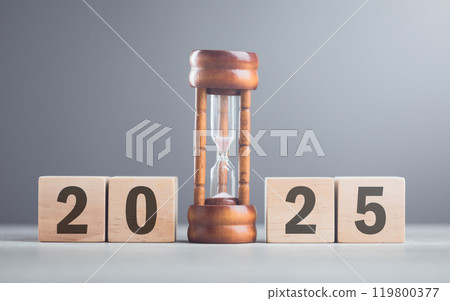 A wooden block displaying '2025' sits beside an hourglass, symbolizing the passage of time and anticipation for the future. Concepts of new beginnings, planning, and the countdown to what's ahead 119800377