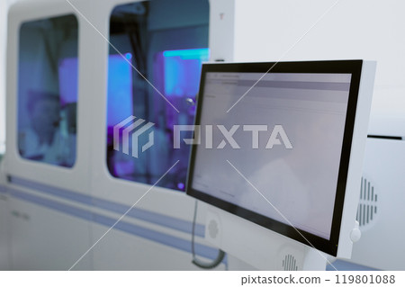 Laboratory technicians working on data analysis in a medical lab environment, with several large monitors and equipment in use 119801088