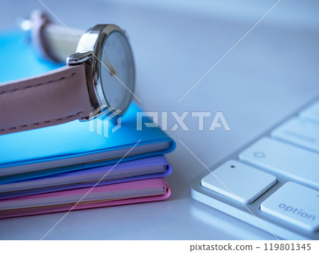 A notebook, keyboard and clock on a table A notebook, keyboard and clock on a table 119801345