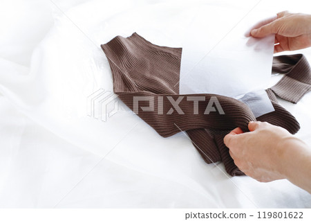 A woman's hands taking a purchased sweater out of a plastic bag 119801622