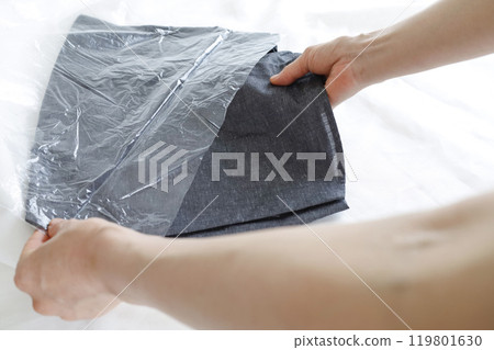 Woman's hands taking clothes out of a plastic bag 119801630