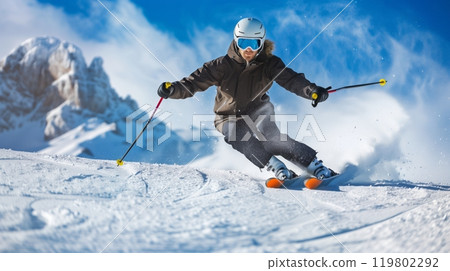 A handsome man skis down a snowy mountain under a crisp blue sky, creating a breathtaking winter scene. 119802292