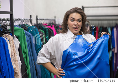 A fat woman chooses clothes in a plus size store.  119802545