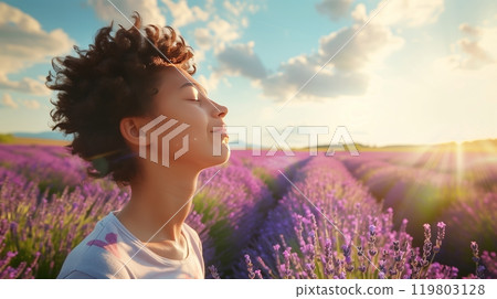 A person stands in a vast lavender field, eyes closed, breathing deeply, and feeling utterly content. 119803128