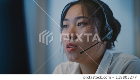 Psychological hotline: Asian helpline specialist in headset listening person Psychological hotline: Asian helpline specialist in headset listening person 119803277