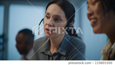 Two female technical support specialists in headsets having conversation with client Two female technical support specialists in headsets having conversation with client 119803300