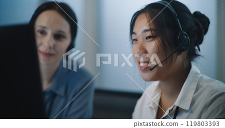 Close up of two female technical support operators in headsets consulting client on call Close up of two female technical support operators in headsets consulting client on call 119803393