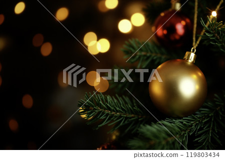 Golden Christmas Ornament on Tree Branch with Festive Lights 119803434