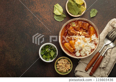 Delicious massaman curry with beef, potatoes, rice, and peanuts is served in bowl top view, Thai cuisine, space for text Delicious massaman curry with beef, potatoes, rice, and peanuts is served in bowl top view, Thai cuisine, space for text 119803436