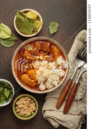 Delicious massaman curry with beef, potatoes, rice, and peanuts is served in bowl top view, Thai cuisine 119803447