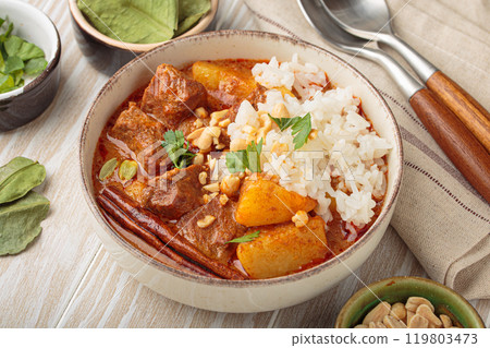Bowl of delicious massaman curry with rice and peanuts on white wooden background, dish of thailand Bowl of delicious massaman curry with rice and peanuts on white wooden background, dish of thailand 119803473