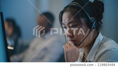 Stressed Asian female hotline operator in headset providing psychological help 119803484