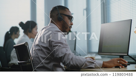 Side view of African American hotline operator talking on headset with customer 119803488