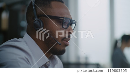 Close up of African American hotline operator in headset having conversation on call Close up of African American hotline operator in headset having conversation on call 119803505