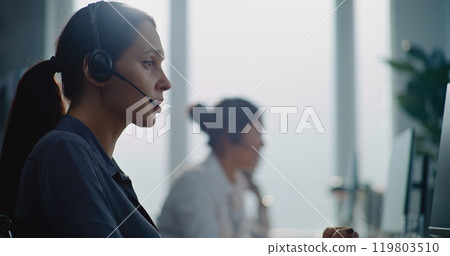 Caucasian female technical customer support operator working on computer, talking on headset Caucasian female technical customer support operator working on computer, talking on headset 119803510