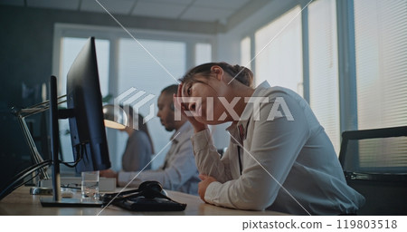 Stressed Asian hotline operator finishing phone call, holding head 119803518