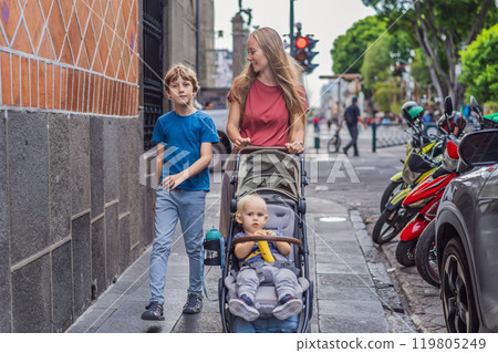 Mother tourist with her toddler and teenage sons walking through the colorful colonial streets of Puebla, Mexico. Travel, cultural exploration, and vibrant architecture concept 119805249