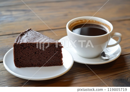 a piece of chocolate sponge cake on a saucer next to a cup of coffee a piece of chocolate sponge cake on a saucer next to a cup of coffee 119805719