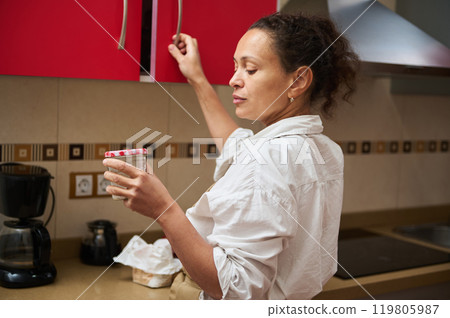 Woman reaching for a jar in a modern kitchen setting Woman reaching for a jar in a modern kitchen setting 119805987