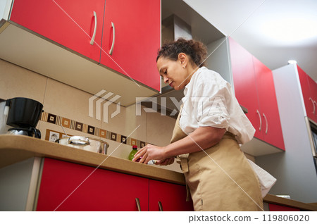 Home cook preparing a meal in modern kitchen with red cabinets 119806020
