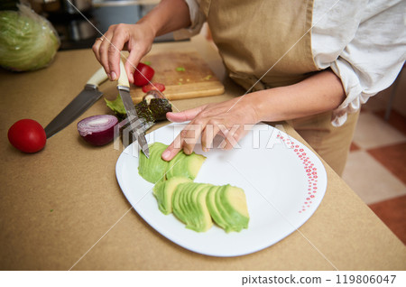 Woman preparing fresh avocado slices in a home kitchen Woman preparing fresh avocado slices in a home kitchen 119806047