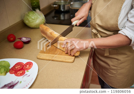 Woman preparing fresh sandwich with vegetables in kitchen Woman preparing fresh sandwich with vegetables in kitchen 119806056