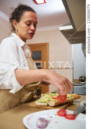 Woman preparing fresh vegetable sandwiches in a modern kitchen Woman preparing fresh vegetable sandwiches in a modern kitchen 119806074