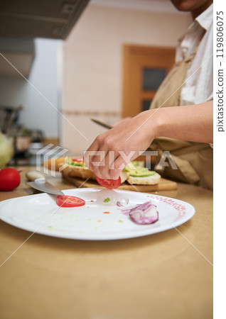 Close-up of hand preparing fresh sandwich in kitchen Close-up of hand preparing fresh sandwich in kitchen 119806075