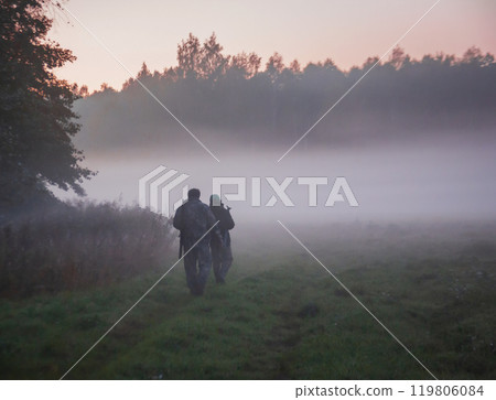 Men in camouflage with weapons move on an autumn morning along edge of field and forest. 119806084