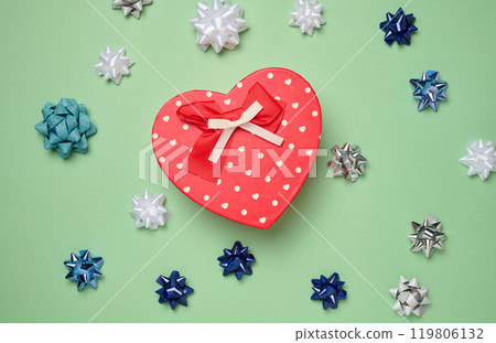Heart shaped gift box and bows on green background, top view Heart shaped gift box and bows on green background, top view 119806132